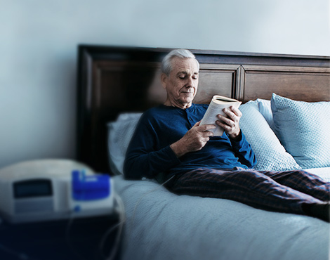 Patient reading a book in bed while performing APD therapy
